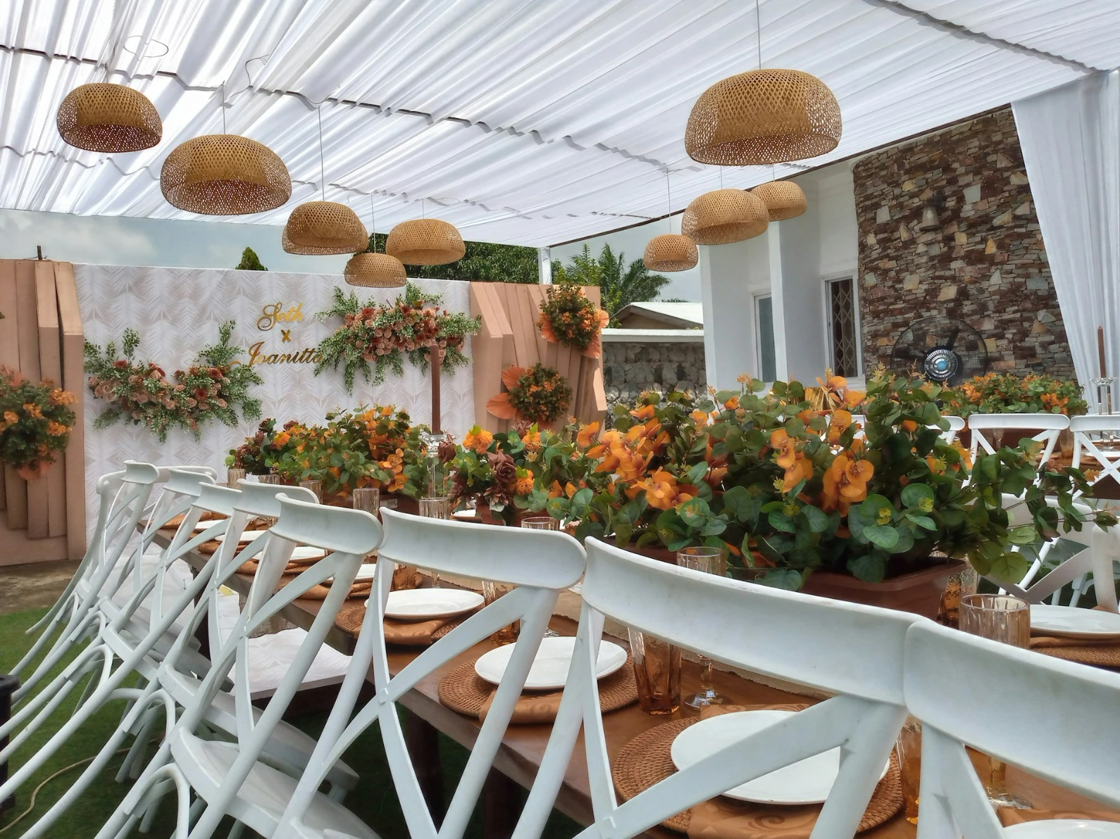 a patio with white chairs and a white table with flowers on it